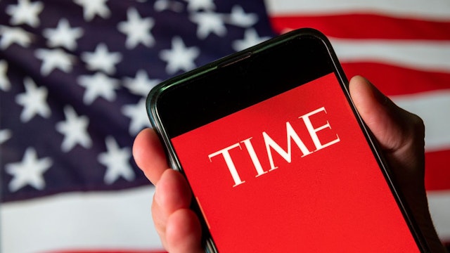 In this photo illustration the American weekly news magazine and news website Time logo is seen on an Android mobile device with United States of America flag in the background.