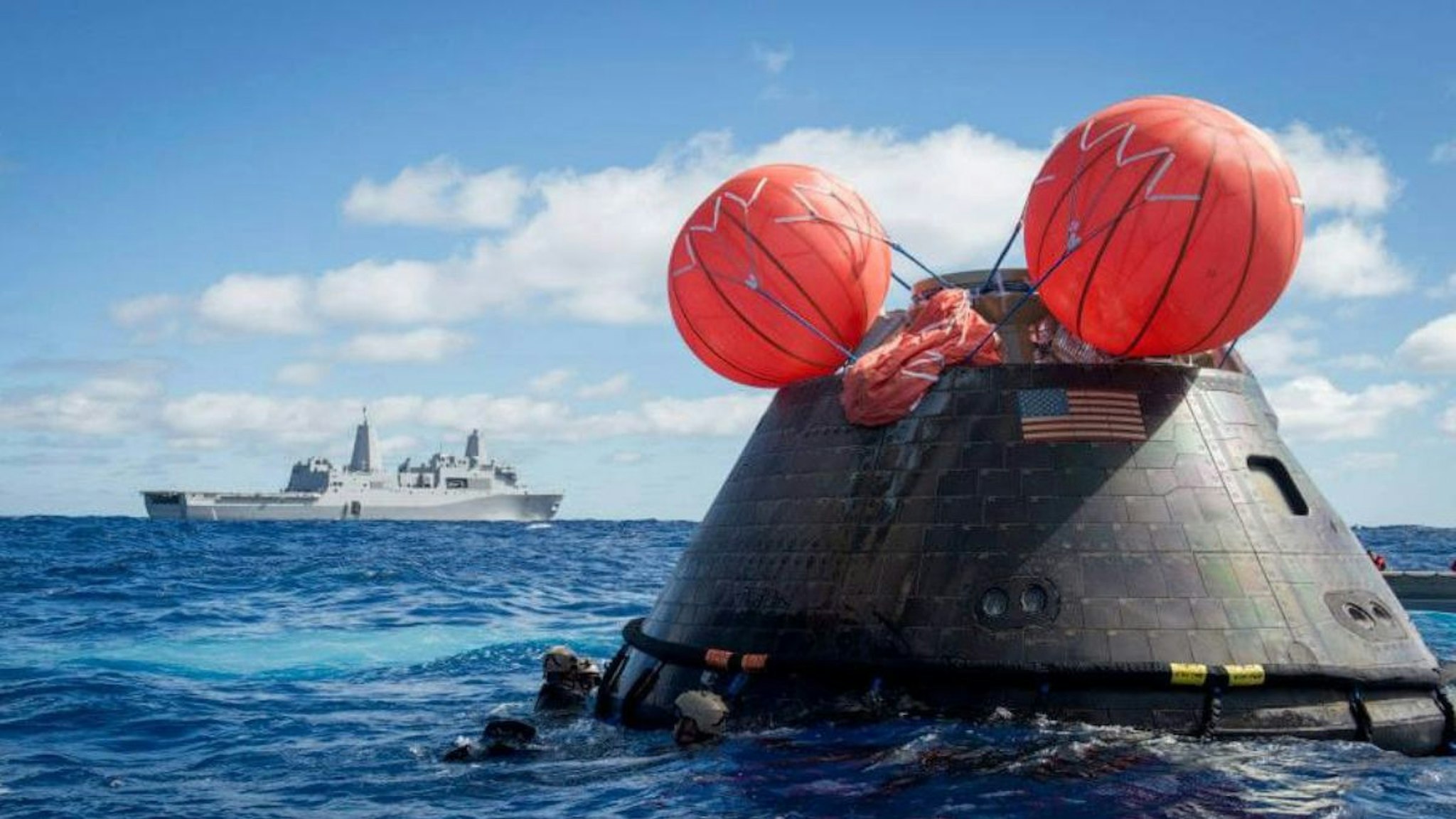In this handout provided by U.S. Navy, Navy divers, assigned to Explosive Ordnance Disposal Mobile Unit 11 (EODMU11), Mobile Dive and Salvage Company 11-7, attach a towing bridal to the Orion Crew Module during the first Exploration Flight Test (EFT-1) NASA Orion Program following its launch from Cape Canaveral Air Force Station's Space Launch Complex 37 December 5, 2014 in the Pacific Ocean, 600 miles southwest of San Diego.