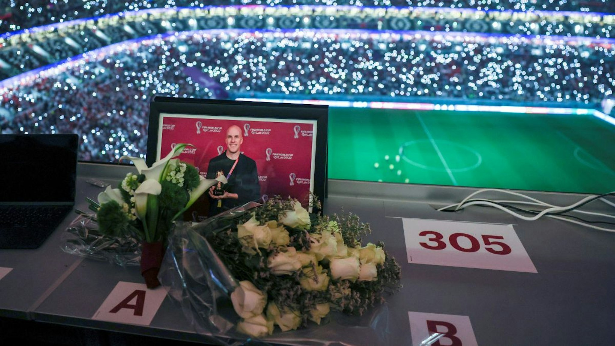 Flowers and a picture of the journalist Grant Wahl of the United States who collapsed and died in the stadium's press area while covering the match between Argentina and Netherlands are seen in the media tribune during the Quarterfinal between England and France at the 2022 FIFA World Cup at Al Bayt Stadium in Al Khor, Qatar, Dec. 10, 2022.