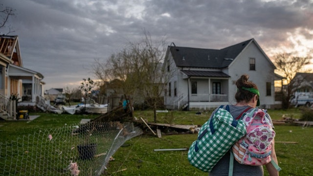 Meg Akenson, 36, travels from her tornado-damaged home, carrying her child's backpack, in the Arabi neighborhood on March 24, 2022 in New Orleans, Louisiana.