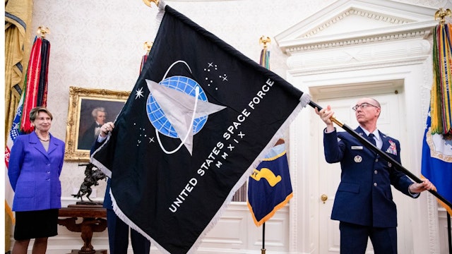 Chief Master Sgt. Roger Towberman (R), Space Force and Command Senior Enlisted Leader and CMSgt Roger Towberman (L), with Secretary of the Air Force Barbara Barrett present US President Donald Trump with the official flag of the United States Space Force in the Oval Office of the White House in Washington, DC on May 15, 2020.