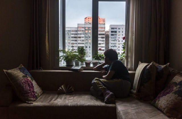 A woman in Vladivostok, Russia looks out of the window at road outside her apartment in the times of corona virus