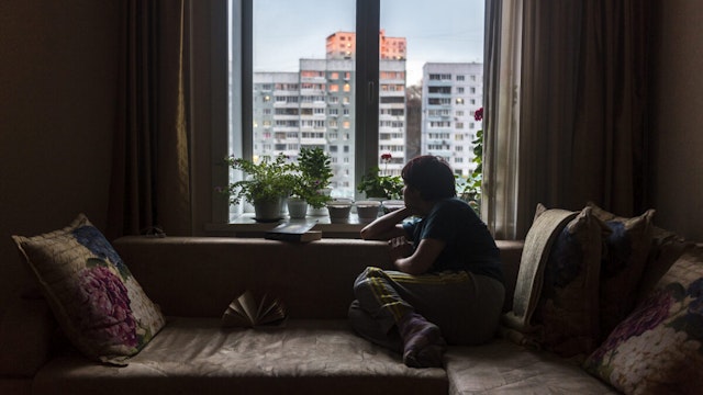 A woman in Vladivostok, Russia looks out of the window at road outside her apartment in the times of corona virus