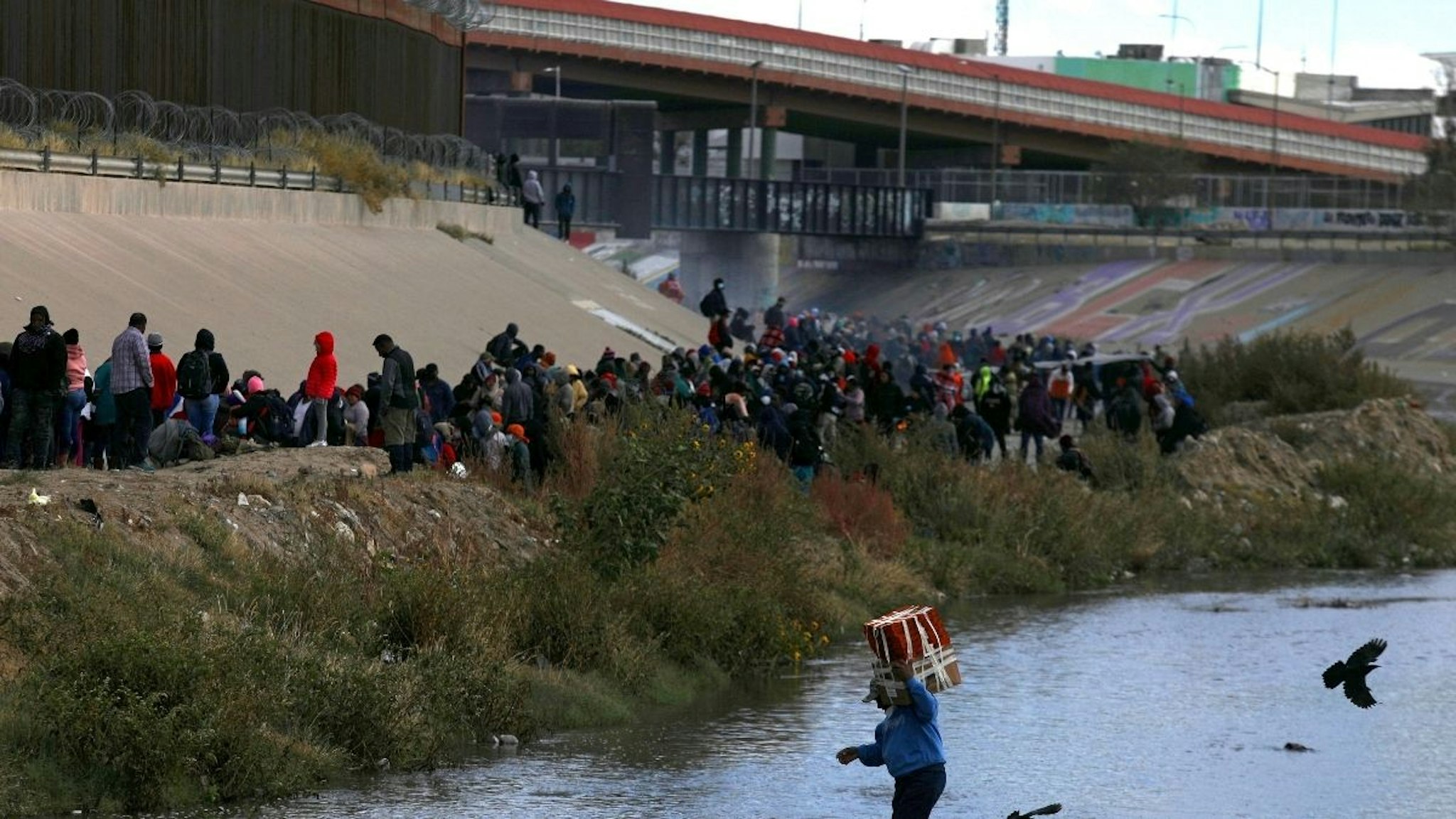 Migrants walk across the Rio Grande to surrender to US Border Patrol agents in El Paso, Texas, as seen from Ciudad Juarez, Chihuahua state, Mexico, on December 13, 2022.