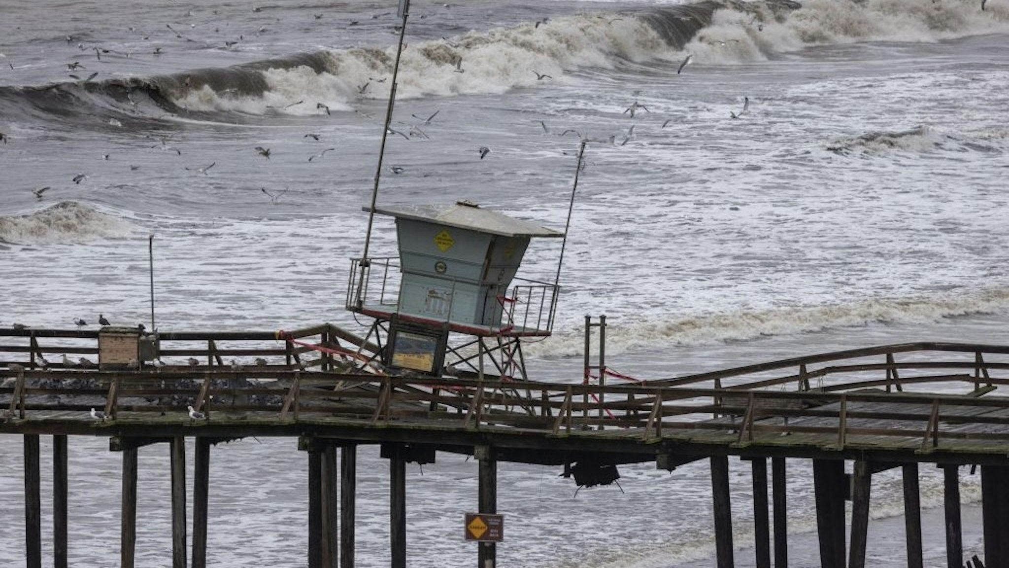 TOPSHOT-US-WEATHER-CALIFORNIA TOPSHOT - This aerial view shows the damaged lifeguard tower on the Seacliff peer after recent storms in Aptos, California, on January 15, 2023. - Soggy Californians on Sunday wearily endured their ninth successive storm in a three-week period that has brought destructive flooding, heavy snowfalls and at least 19 deaths, and forecasters said more of the same loomed for another day. (Photo by DAVID MCNEW / AFP) (Photo by DAVID MCNEW/AFP via Getty Images) DAVID MCNEW / Contributor Photo by DAVID MCNEW / Contributor/AFP / DAVID MCNEW / AFP via Getty Images
