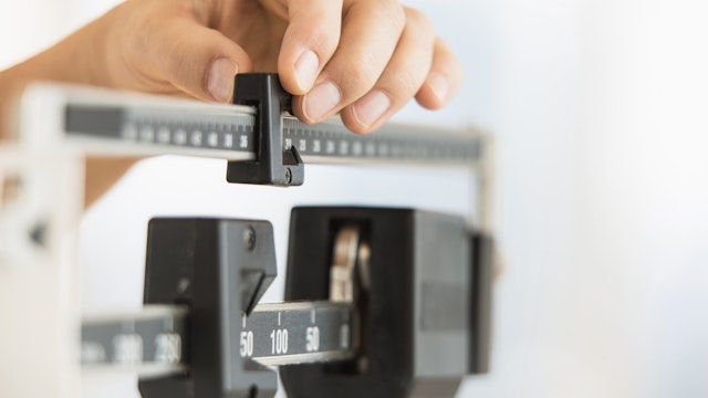 Hand adjusting weight scales - stock photo Tetra Images via Getty Images
