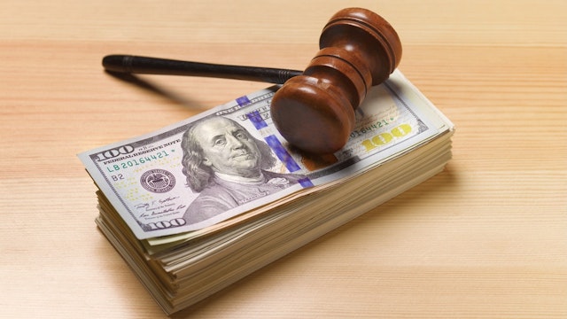 Gavel sitting on pile of dollar notes - stock photo judges/auctioneer's gavel with a pile of dollars Peter Dazeley via Getty Images
