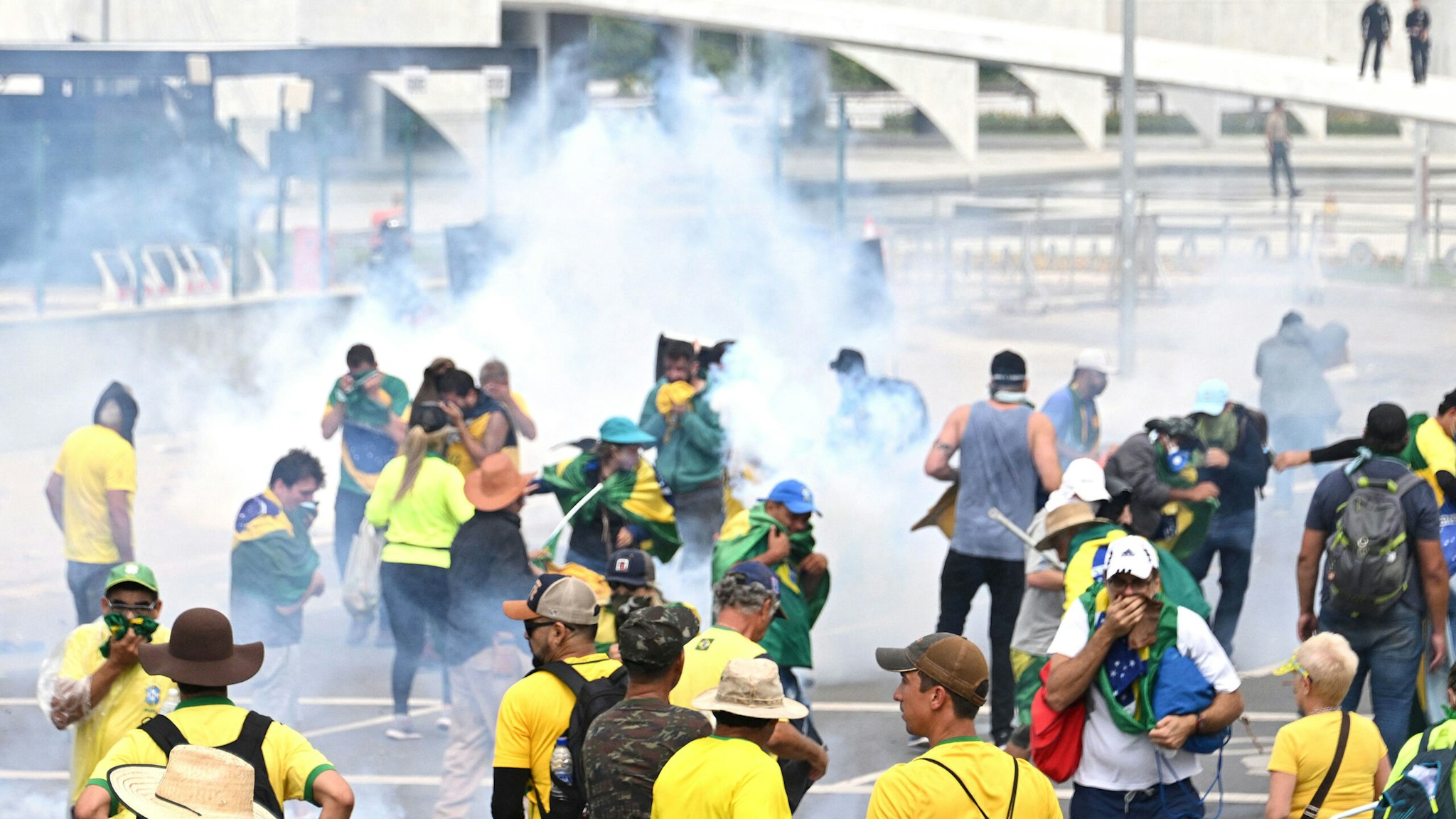 Supporters of Brazilian former President Jair Bolsonaro clash with the police during a demonstration outside the Planalto Palace in Brasilia on January 8, 2023. - Brazilian police used tear gas Sunday to repel hundreds of supporters of far-right ex-president Jair Bolsonaro after they stormed onto Congress grounds one week after President Luis Inacio Lula da Silva's inauguration, an AFP photographer witnessed.