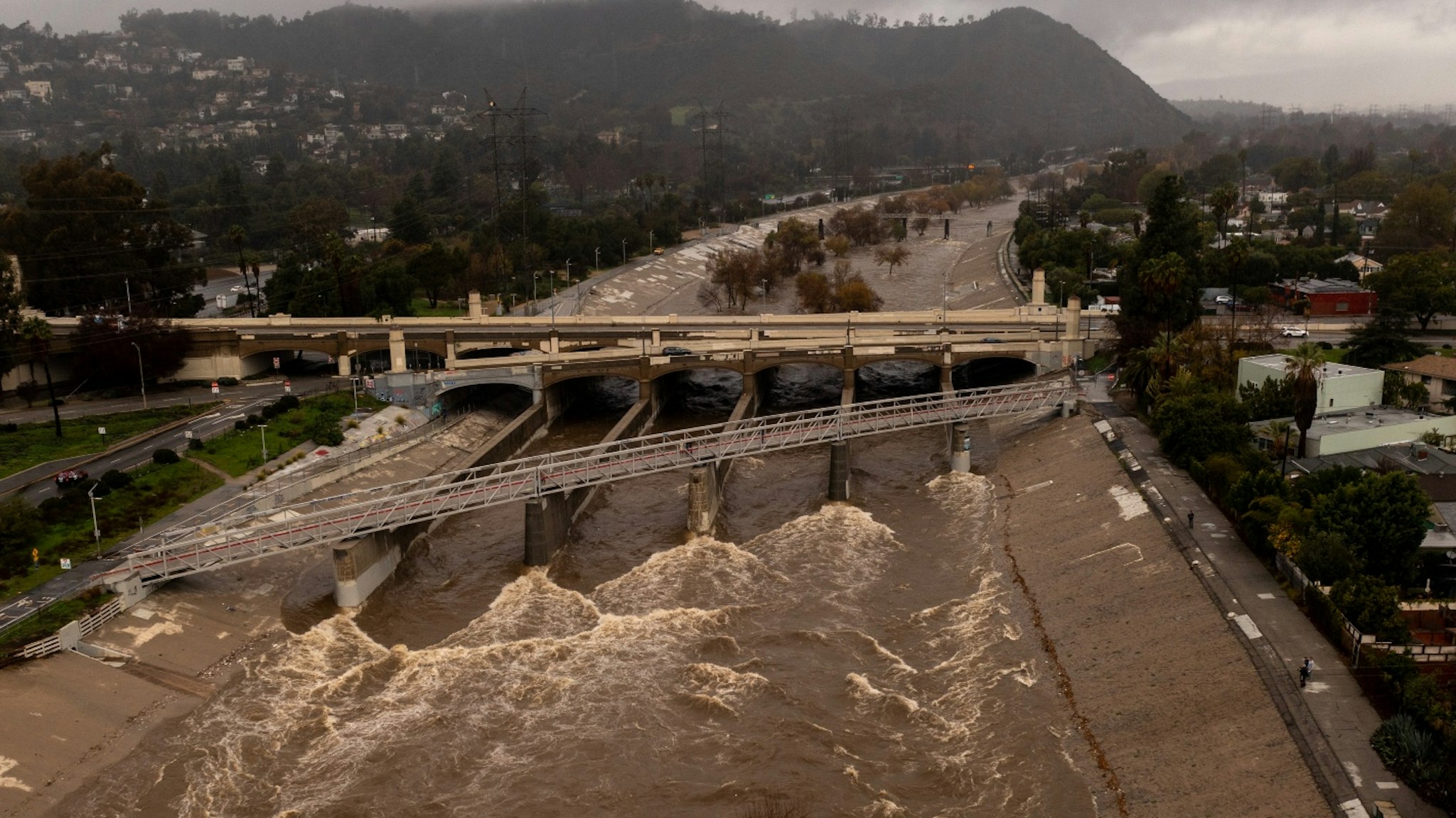 In an aerial view, the Los Angeles River flows at a powerful rate as a huge storm slams into the West Coast on January 5, 2023 in Los Angeles, California. The dangerous storm condition has prompted California Gov. Gavin Newsom to declare a state of emergency.