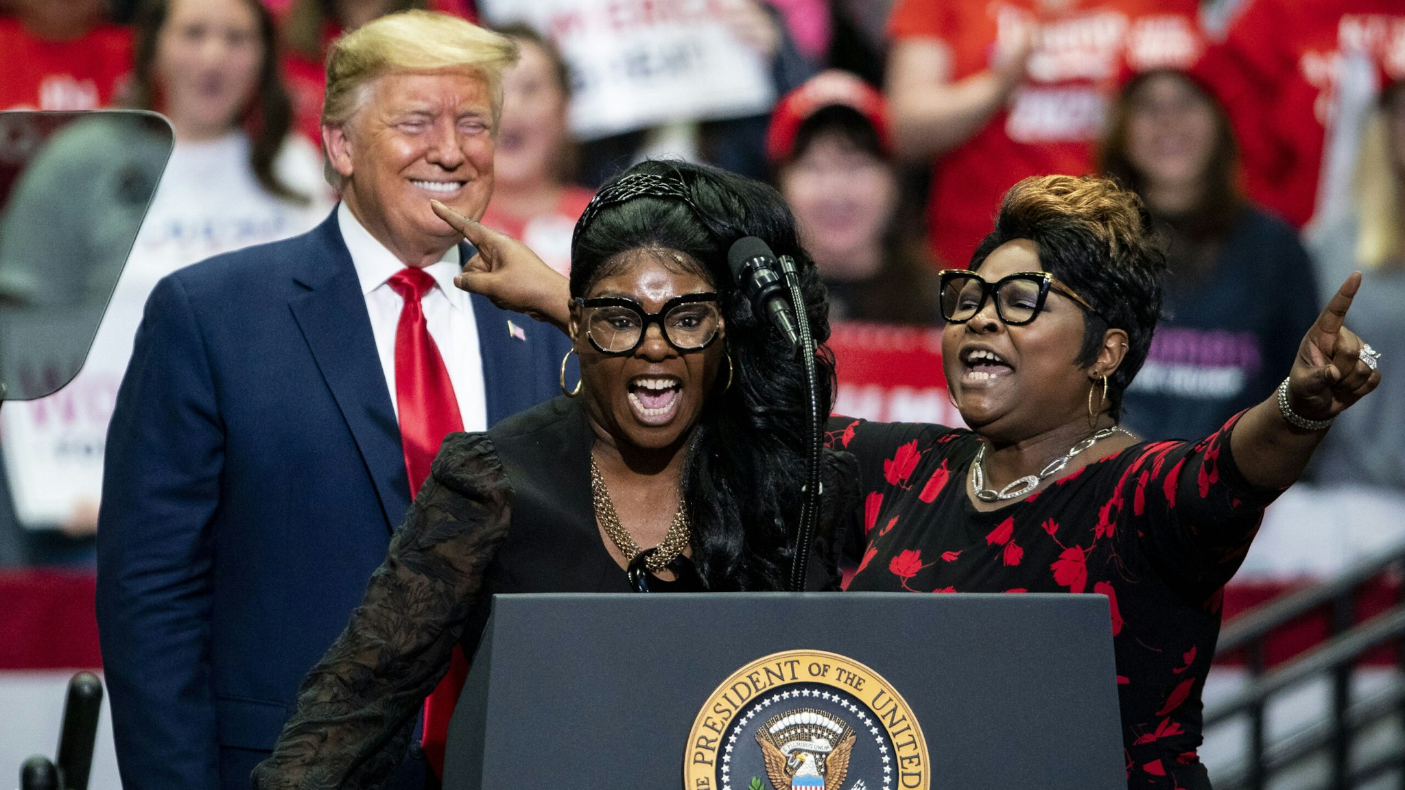 Social Media influencers and video bloggers Lynnette "Diamond" Hardaway, center, and Rochelle "Silk" Richardson, right, speak as U.S. President Donald Trump smiles during a rally in Charlotte, North Carolina, on Monday, March 2, 2020. Trump told reporters in the Oval Office on Monday that holding campaign rallies with thousands of attendees is "very safe" despite recent cases of the virus in the U.S.