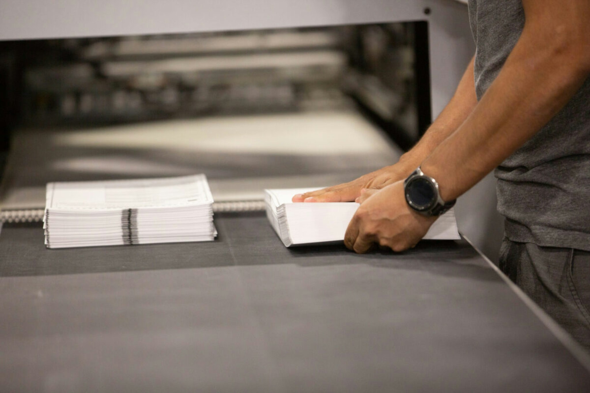 A worker straightens a stack of ballots as they come off the printer at the Runbeck Election Services facility in Phoenix, Arizona, U.S., on Tuesday, June 23, 2020.