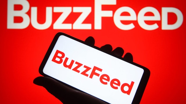 In this photo illustration, BuzzFeed Inc. logo is seen on a smartphone and a computer screen.
