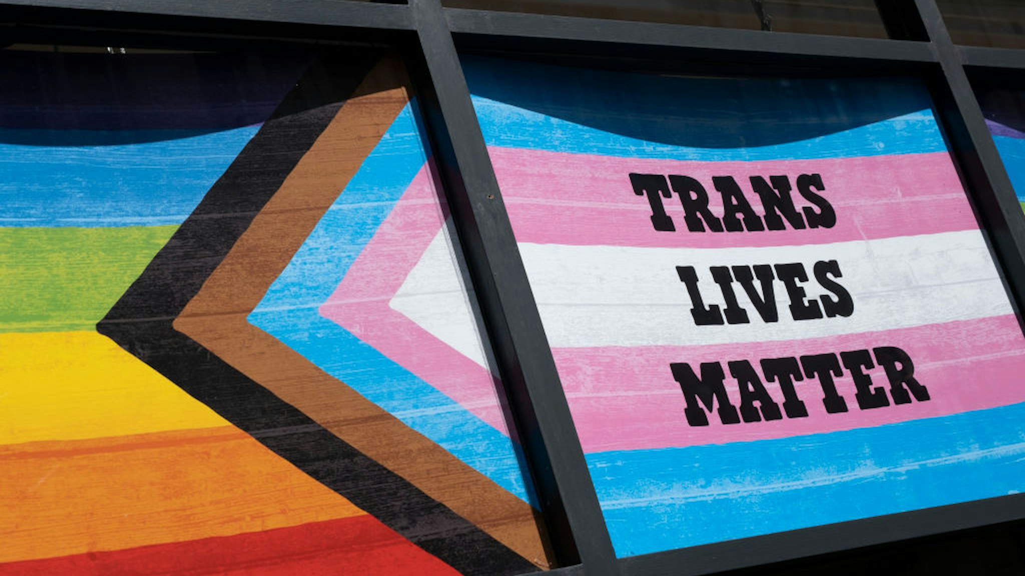 Pride Progress flag alongside the Transgender Pride flag with the slogan 'Trans Lives Matter' in Soho on 28th June 2022 in London, United Kingdom. The flag includes the rainbow flag stripes to represent LGBTQ+ communities, with colors from the Transgender Pride Flag and to also represent people of colour. The transgender flag is a light blue, pink and white pentacolour pride flag representing the transgender community, organizations, and individuals. (photo by Mike Kemp/In Pictures via Getty Images)
