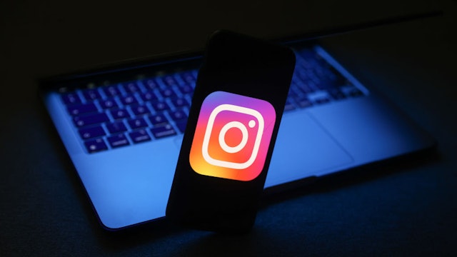 Instagram logo displayed on a phone screen and a laptop are seen in this illustration photo taken in Krakow, Poland on November 27, 2022.
