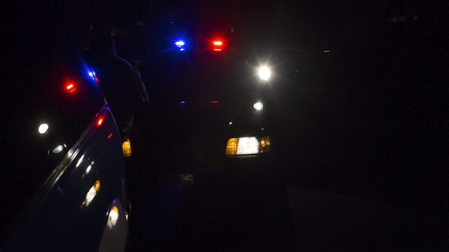 Nighttime view of police car, it's lights reflected on a suspect's vehicle, Los Angeles, California, February 1, 2013.