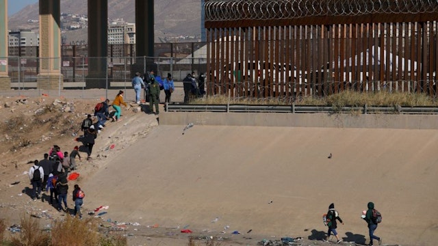 Migrants wait in line to be processed by the Border Patrol along the border wall after crossing the Rio Grande river into El Paso, Texas on the US-Mexico border as seen from Ciudad Juarez, Chihuahua state, Mexico on December 19, 2022. - The US Supreme Court halted December 19, 2022 the imminent removal of Title 42, a key policy used since the administration of president Donald Trump to block migrants at the southwest border, amid worries over a surge in undocumented immigrants. (Photo by HERIKA MARTINEZ / AFP) (Photo by HERIKA MARTINEZ/AFP via Getty Images)