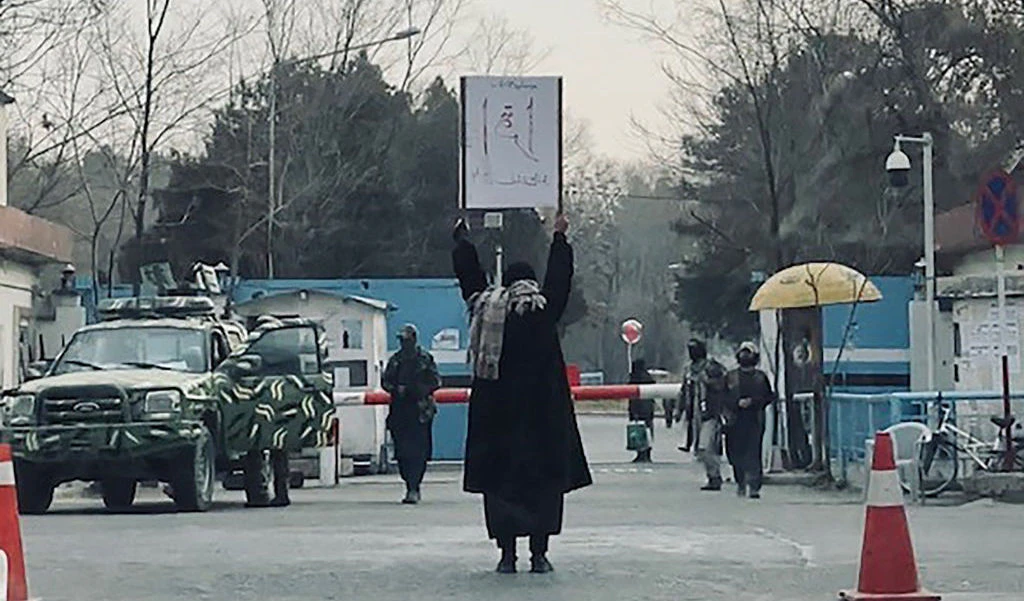 TOPSHOT - This picture taken on December 25, 2022 shows student Marwa protesting alone against the ban on women's higher education, outside the Kabul University as members of Taliban stand guard in Kabul. - An 18-year-old Afghan student endured Taliban taunts and insults at the weekend as she staged a solo protest against the ban on women attending university. "For the first time in my life, I felt so proud, strong and powerful because I was standing against them and demanding a right that God has given us," Marwa told AFP, asking not to be further identified. (Photo by AFP) (Photo by -/AFP via Getty Images)