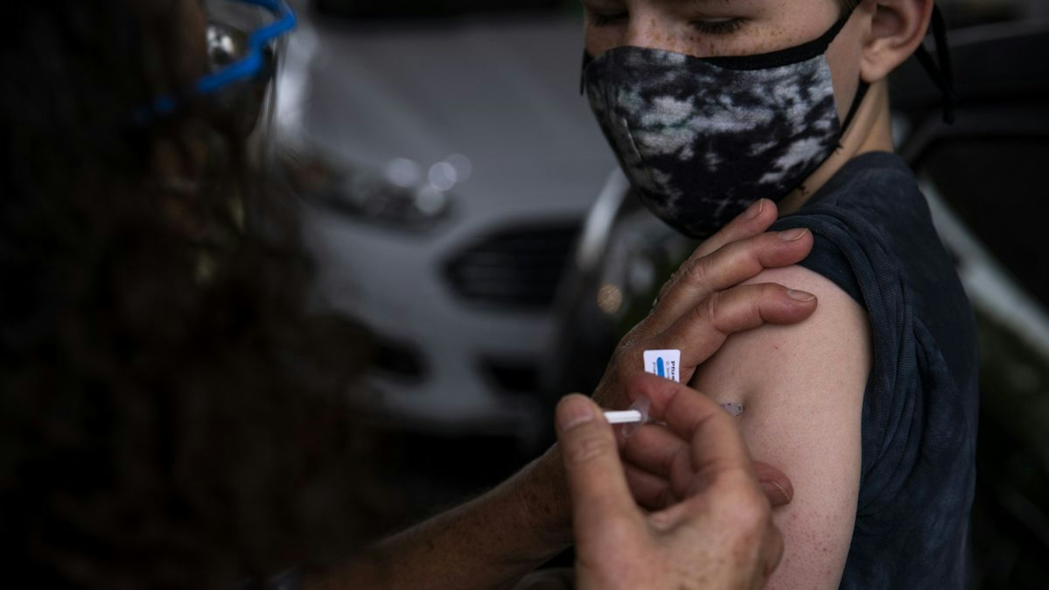 A healthcare worker administers a dose of the Pfizer-BioNTech Covid-19 vaccine to a teenager at the Oregon Health & Science University (OHSU) mass vaccination site at Portland International Airport (PDX) in Portland, Oregon, U.S., on Monday, May 17, 2021.