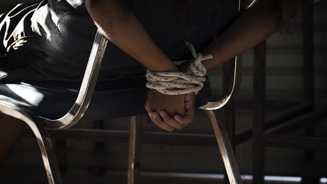 Midsection Of Woman Tied Up With Rope On Chair In Room - stock photo