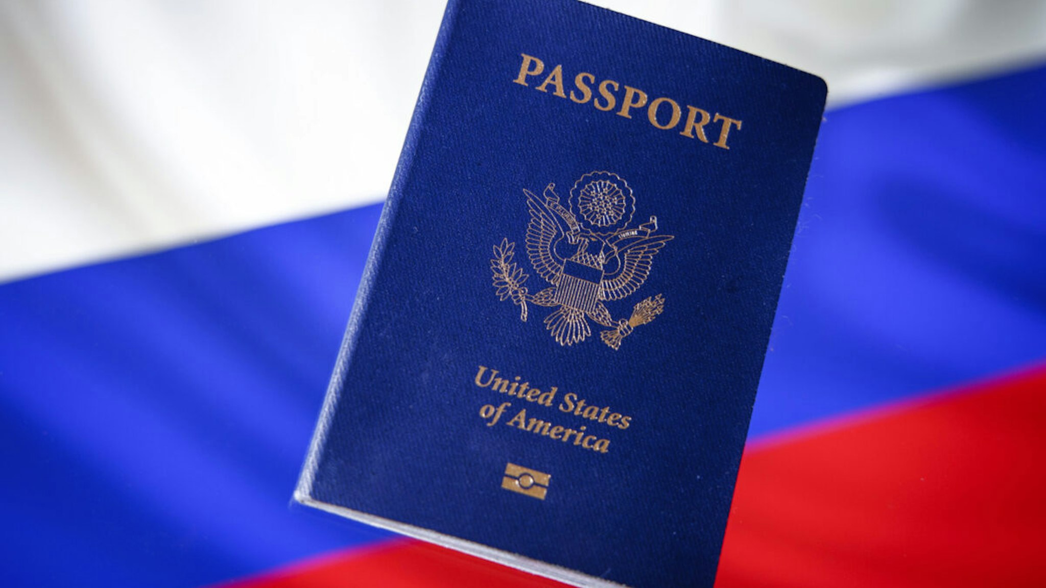 An American US passport is seen in this photo illustration with a Russian flag in the background in Warsaw, Poland on 29 September, 2022.