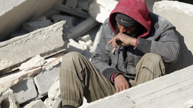 A Syrian man sits amidst the rubble as he waits for new about family members stuck under the wreckage in the town of Harim in Syria's rebel-held northwestern Idlib province on the border with Turkey, on February 8, 2023, two days after a deadly earthquake that hit Turkey and Syria.