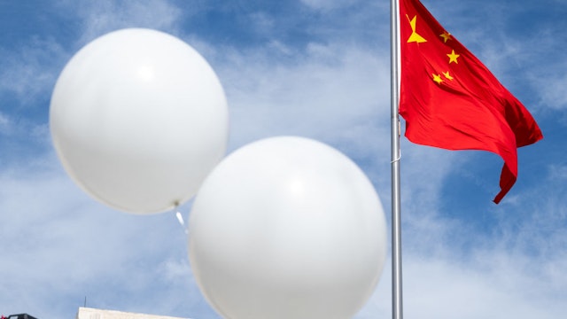 Two white balloons float near the Chinese flag as activist Rev. Patrick Mahoney protests against the Chinese government over the alleged Chinese surveillance balloon that was shot down over the US last week, during a demonstration outside the Chinese Embassy in Washington, DC, February 15, 2023. (Photo by SAUL LOEB / AFP) (Photo by SAUL