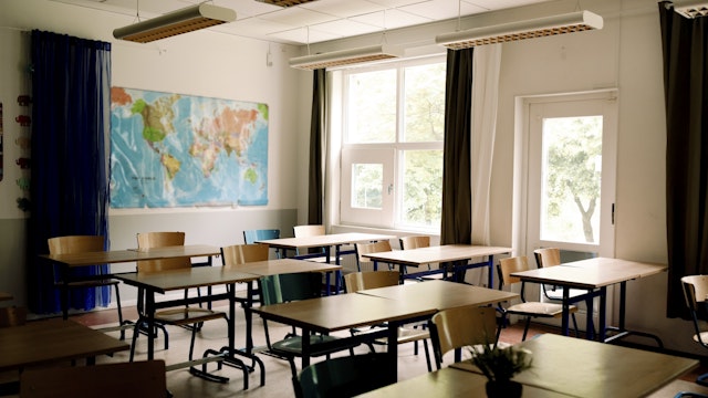 Desks and chairs arranged in classroom at high school - stock photo