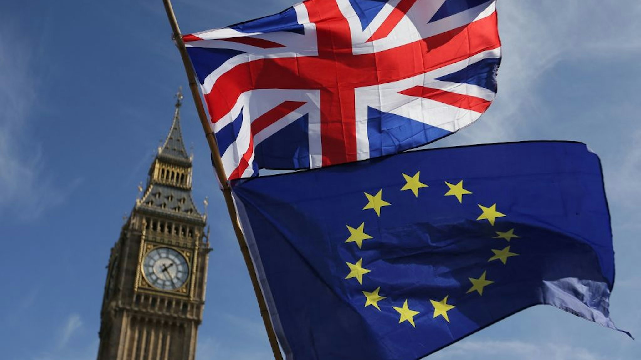 TOPSHOT - An EU flag and a Union flag held by a demonstrator is seen with Elizabeth Tower (Big Ben) and the Houses of Parliament as marchers taking part in an anti-Brexit, pro-European Union (EU) enter Parliament Square in central London on March 25, 2017, ahead of the British government's planned triggering of Article 50 next week. - Britain will launch the process of leaving the European Union on March 29, setting a historic and uncharted course to become the first country to withdraw from the bloc by March 2019.