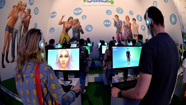Visitors try out the game 'SIMS 4' at the Electronic Arts stand at the 2014 Gamescom gaming trade fair on August 14, 2014 in Cologne, Germany