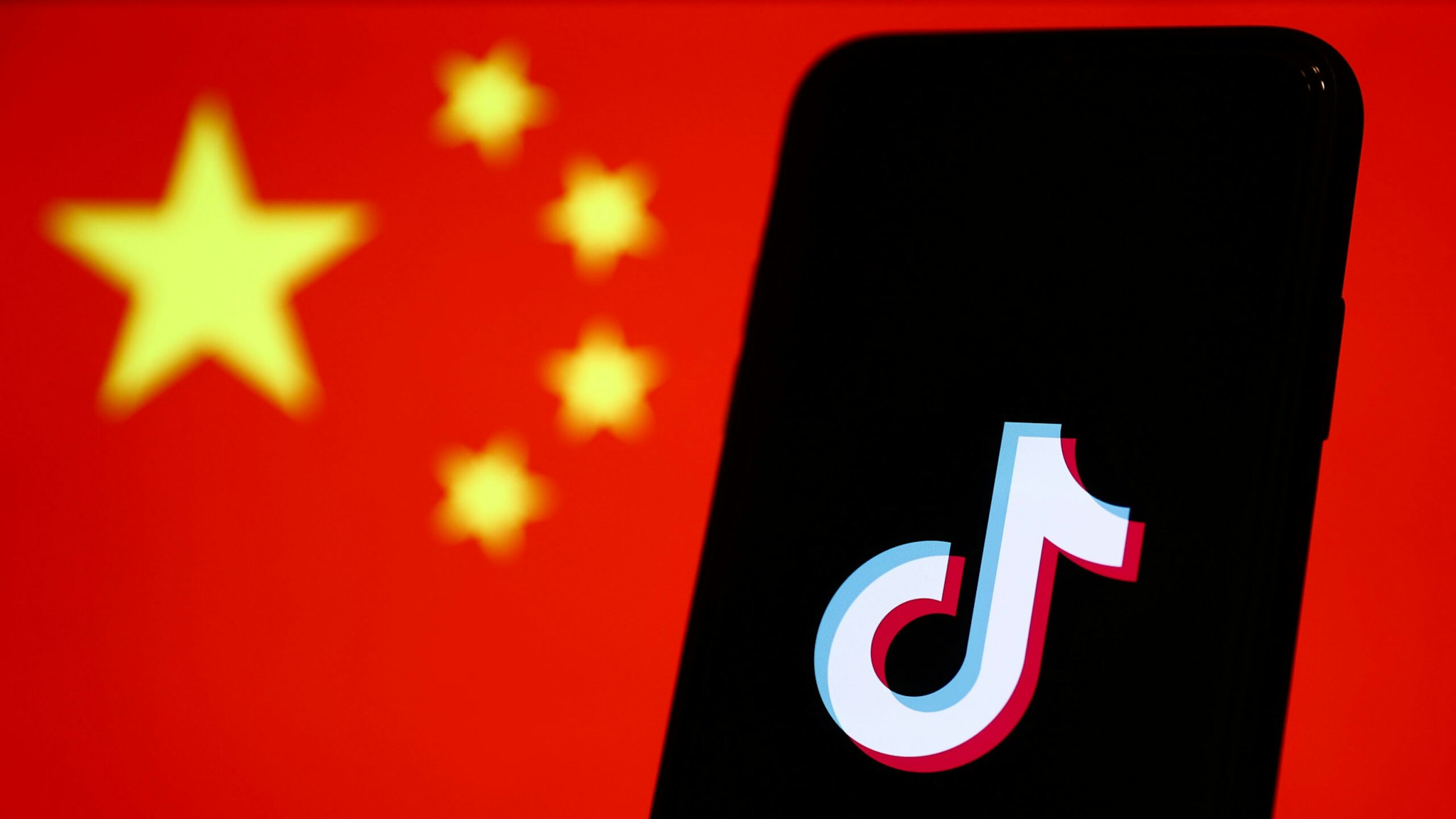 TikTok logo displayed on a phone screen and Chinese flag displayed on a screen in the background are seen in this illustration photo taken in Krakow, Poland on January 30, 2023.