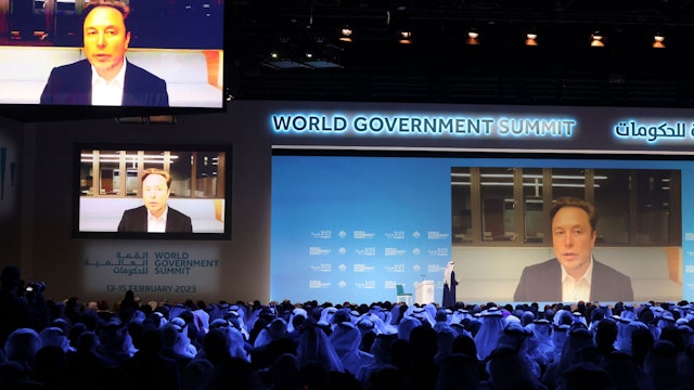 UAE Minister of Cabinet Affairs Mohammad al-Gergawi (L-on stage) speaks with Elon Musk attending the World Government Summit virtually in Dubai on February 15, 2023. (Photo by Karim SAHIB / AFP)