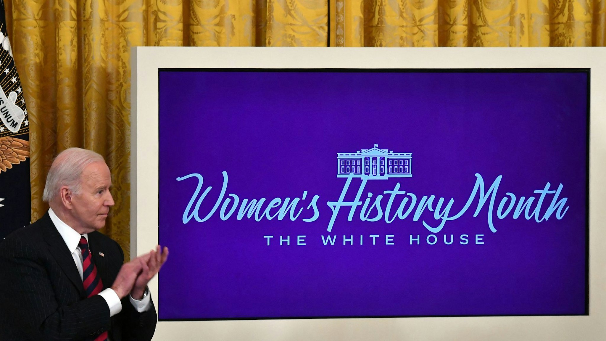 US President Joe Biden applauds as US First Lady Jill Biden (out of frame) speaks during the Equal Pay Day event to celebrate Womens History Month in the East Room of the White House in Washington, DC, March 15, 2022.