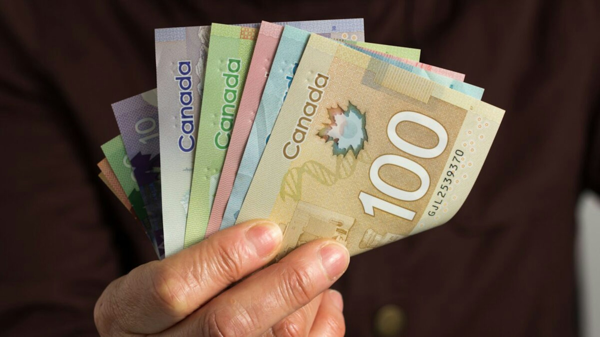 Money from Canada: Canadian Dollars. Old retired person paying in cash.