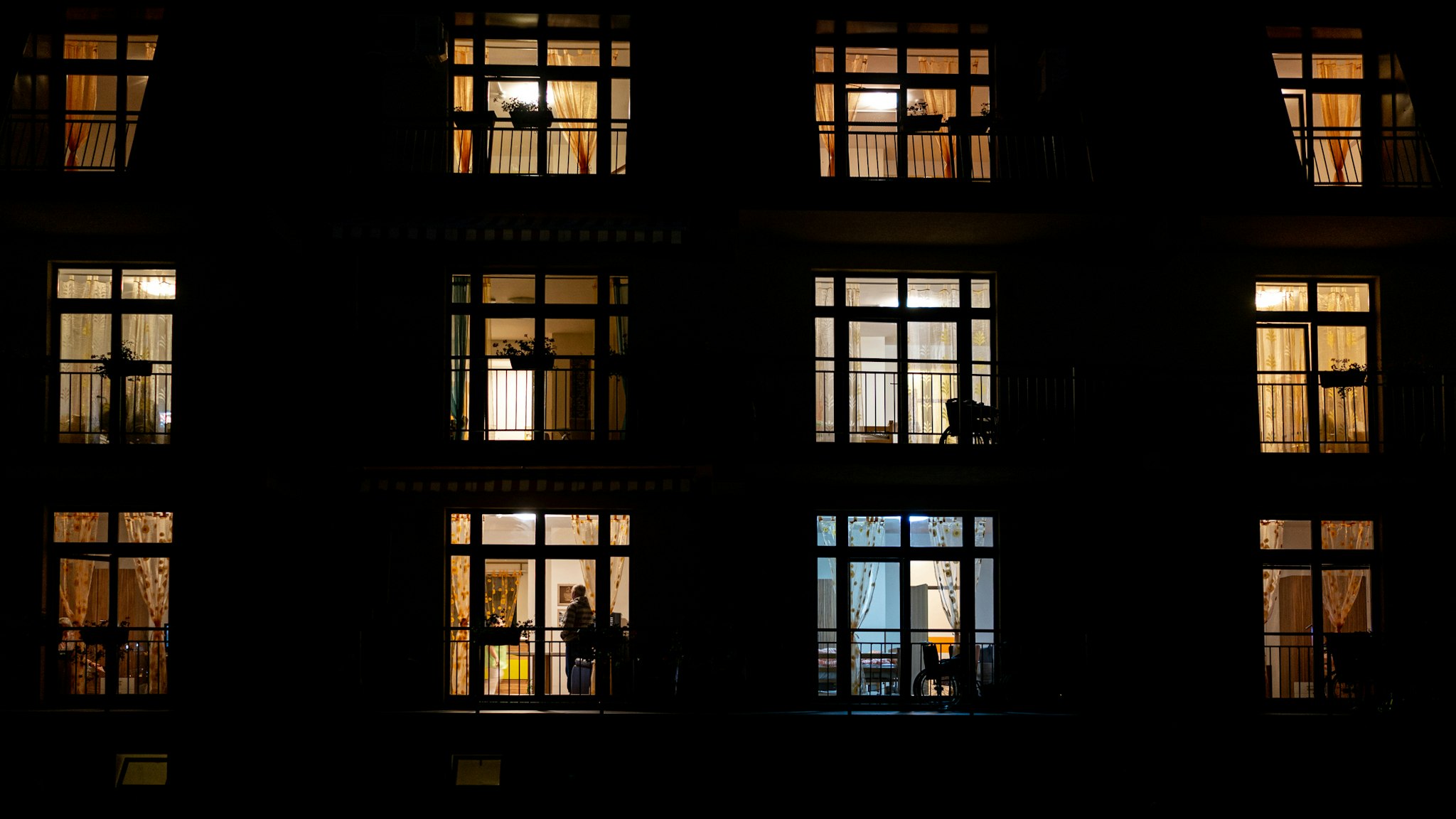 Illuminated windows of night house with people inside - stock photo