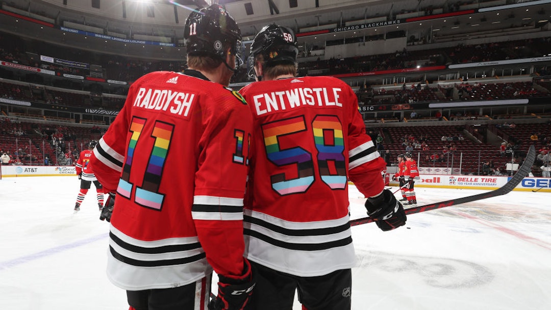 CHICAGO, ILLINOIS - APRIL 12: Taylor Raddysh #11 and MacKenzie Entwistle #58 of the Chicago Blackhawks warm up with rainbow colors on their jersey in honor of Pride Night, prior to the game against the Los Angeles Kings at United Center on April 12, 2022 in Chicago, Illinois. (Photo by Chase Agnello-Dean/NHLI via Getty Images)
