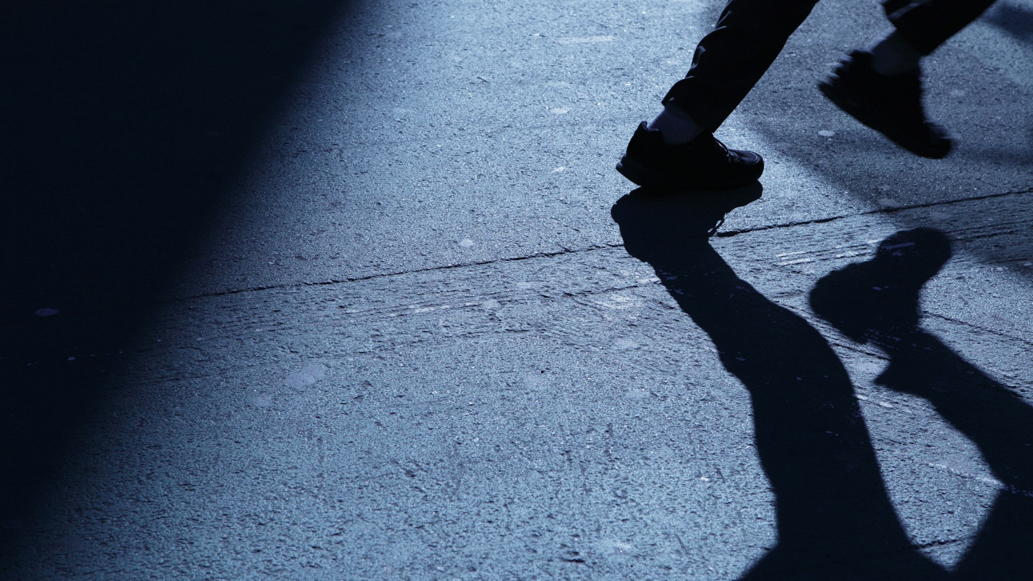Lone man running away in blue night shadows - stock photo
