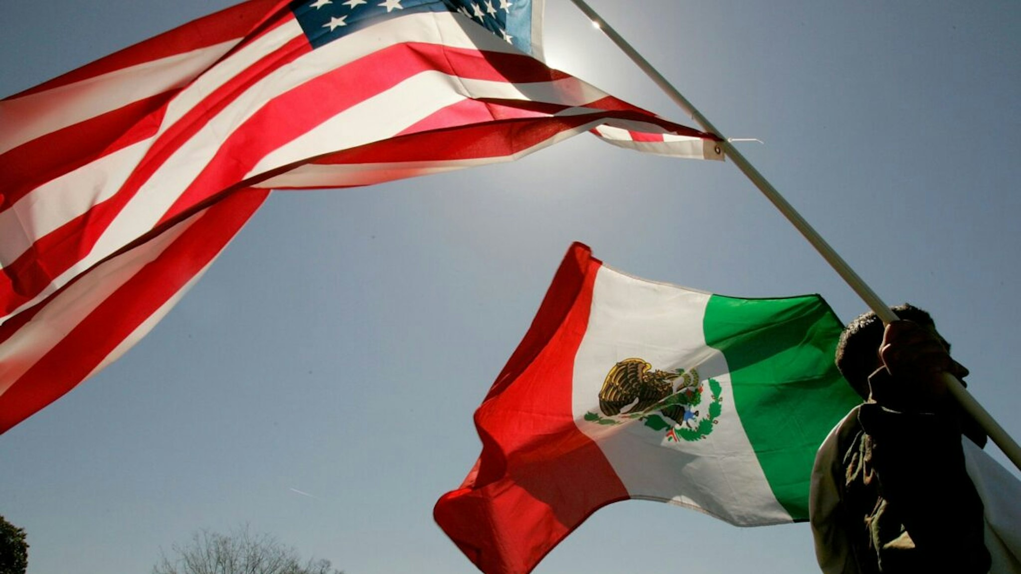 A protester holds an American flag and a Mexican flag while participating in a protest on the west front of the U.S. Capitol March 27, 2006 in Washington, DC