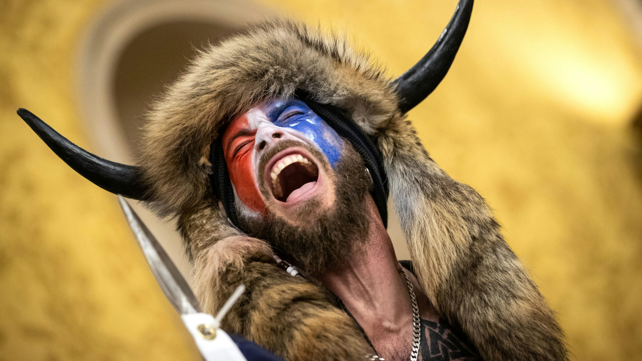 WASHINGTON, DC - JANUARY 06: Jacob Chansley, also known as the "QAnon Shaman," screams "Freedom" inside the U.S. Senate chamber after the U.S. Capitol was breached by a mob during a joint session of Congress on January 6, 2021 in Washington, DC. Congress held a joint session to ratify President-elect Joe Biden's 306-232 Electoral College win over President Donald Trump. Pro-Trump protesters illegally entered the U.S. Capitol building following rallies in the nation's capital.
