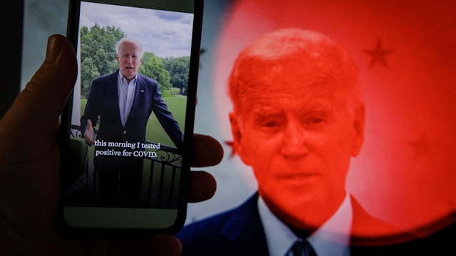 TOPSHOT - In this photo illustration taken on July 21, 2022 in Washington, DC, a video tweet from US President Joe Biden is seen on a cell phone, juxtaposed on a computer screen in the background, with a breaking news alert that the President has tested positive for the coronavirus, - The short video clip filmed on a White House balcony, says: "I really appreciate all your inquiries and concern, but I am doing well... it's going to be OK." Announcing Biden's diagnosis, the White House stressed that the president was fully vaccinated and twice boosted, and said he was "experiencing very mild symptoms."