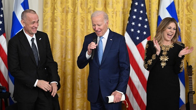 US President Joe Biden speaks at a reception celebrating Greek Independence Day, flanked by actor Tom Hanks and singer Rita Wilson, in the East Room of the White House in Washington, DC, March 29, 2023.