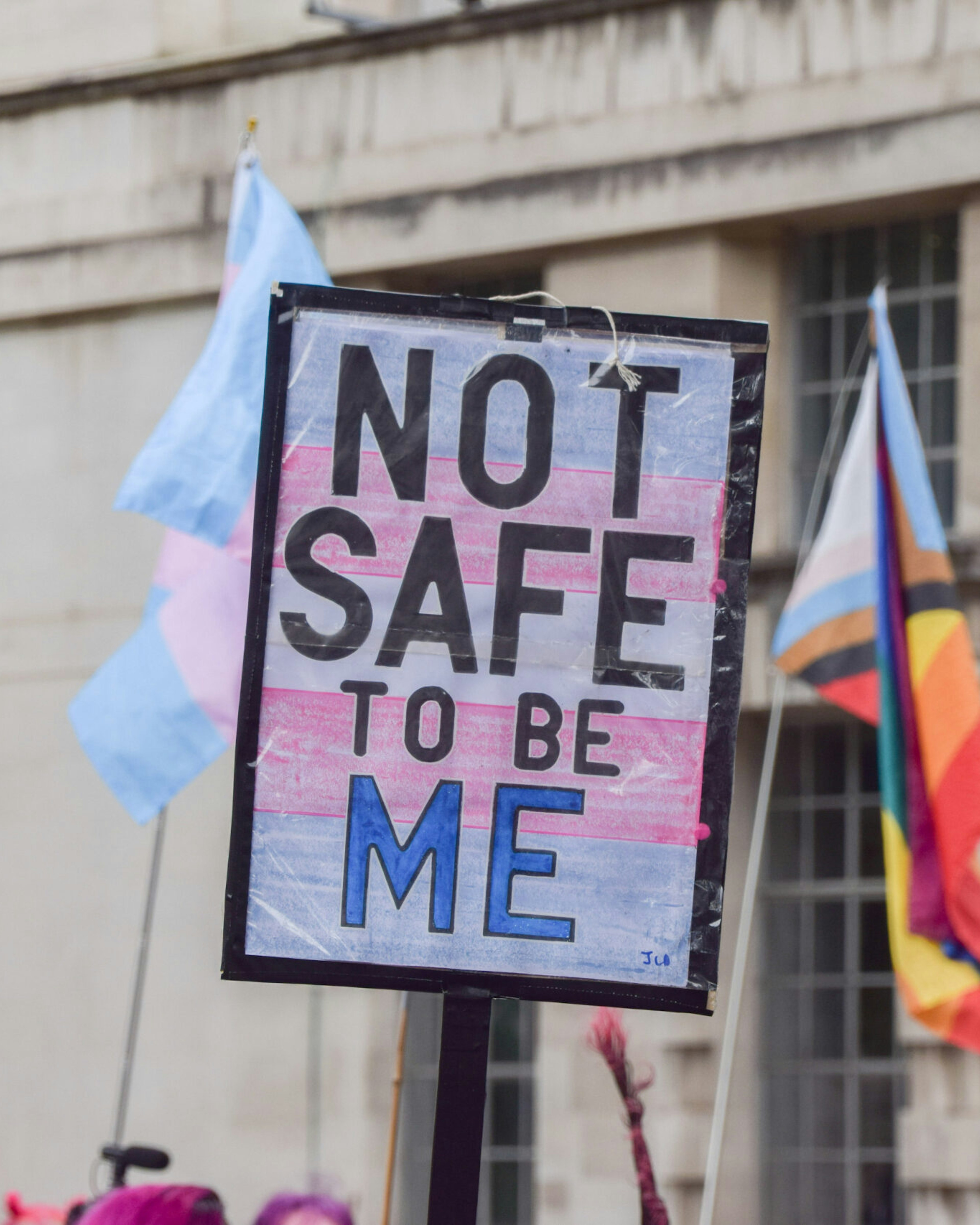 A protester holds a placard with the colours of the trans