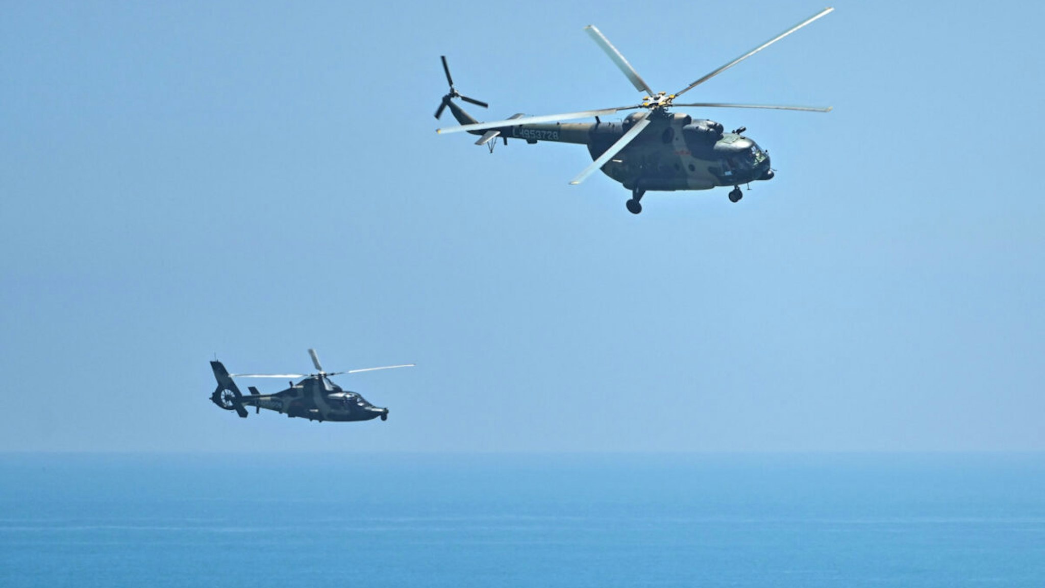 Chinese military helicopters fly past Pingtan island, one of mainland China's closest point from Taiwan, in Fujian province on August 4, 2022, ahead of massive military drills off Taiwan following US House Speaker Nancy Pelosi's visit to the self-ruled island. - China's largest-ever military exercises encircling Taiwan kicked off on August 4, in a show of force straddling vital international shipping lanes after a visit to the island by US House Speaker Nancy Pelosi.
