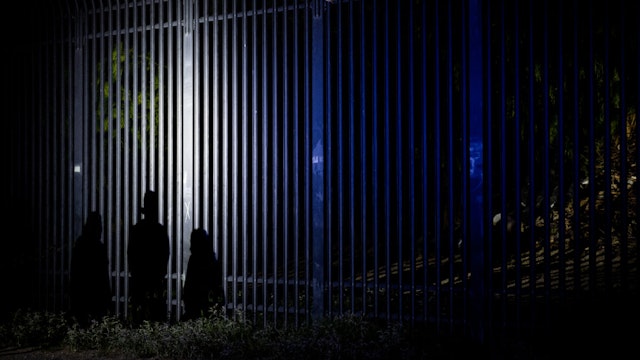 The shadow of migrants is seen illuminated onto border fencing on May 20, 2022 in Eagle Pass, Texas.