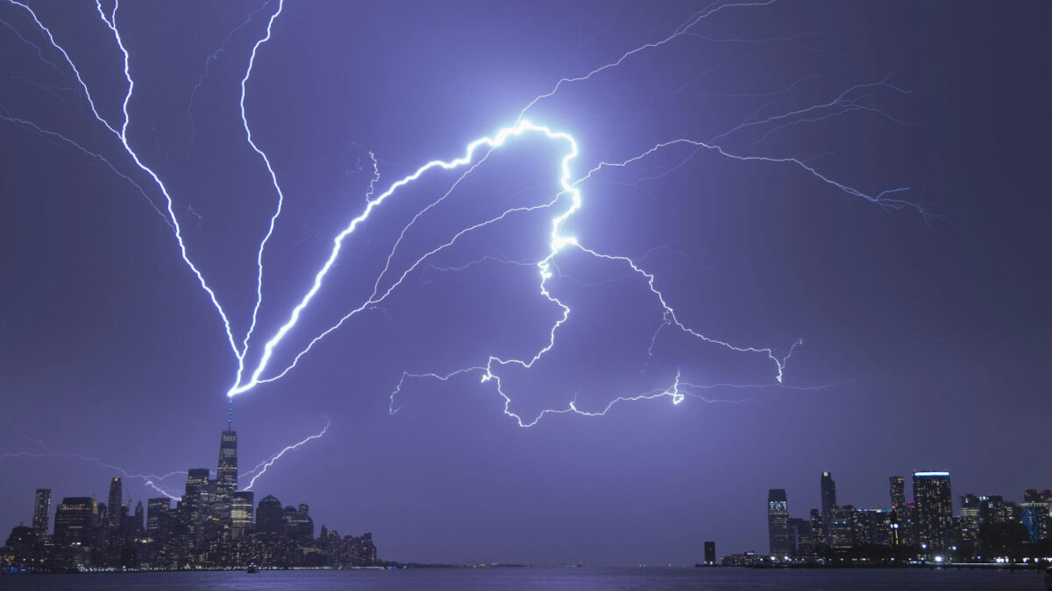 HOBOKEN, NJ - APRIL 1: Lightning bolts strike One World Trade Center in New York City as it fans out over the Hudson River and Jersey City, New Jersey during a thunderstorm on April 1, 2023, as seen from Hoboken, New Jersey.