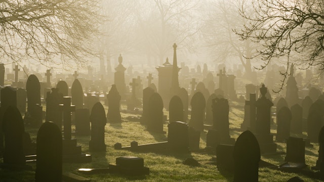 Low winter sunlight flooding through a misty cemetery in Stoke-on-Trent.