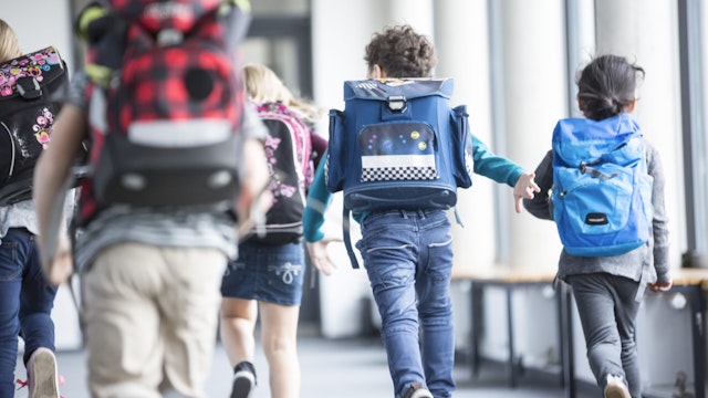 Rear view of pupils rushing down school corridor