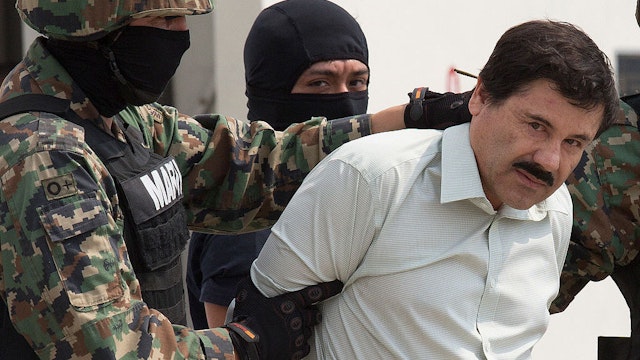 The drug trafficker Joaquin Guzman Loera, El Chapo, looks at the press, guarded by members of Mexican Navy is moved to a helicopter. El chapo, was arrested Saturday at 6:40 hours at a hotel in Mazatlan, Sinaloa in Mexico city, Mexico, on Saturday, Feb. 22, 2014. Photographer: Susana Gonzalez/Bloomberg