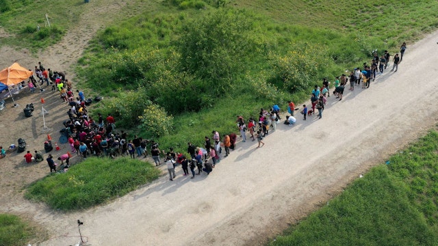 BROWNSVILLE, TEXAS - MAY 10: In this aerial view, migrants stand in line as they wait to be processed by the U.S. Border Patrol after crossing the border from Mexico on May 10, 2023 in Brownsville, Texas. (Photo by Joe Raedle/Getty Images)