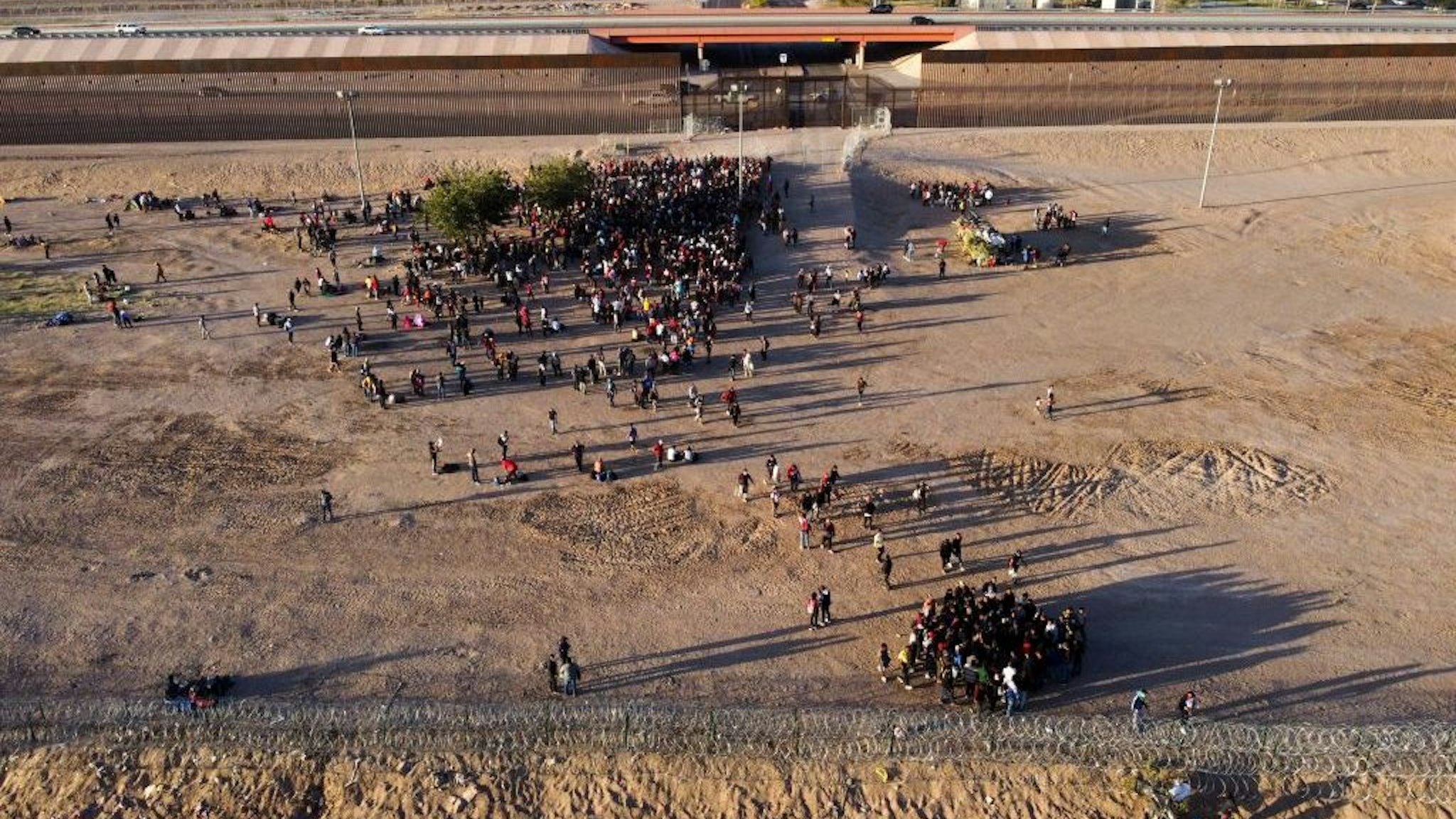 Aerial view of migrants waiting to be processed by the El Paso Sector Border Patrol at the banks of the Rio Grande River in El Paso, Texas, United States, as seen from Ciudad Juarez, Chihuahua State, Mexico, taken on May 4, 2023. Under the intense desert sun, among sand and brush, hundreds of migrants crossed the Rio Grande from Mexico on the rumor that the United States would let them in. But their hopes were dashed as they fell prey, once again, to misinformation. Falsehoods and deceptions add to the ordeal of these people, first to reach the border through Mexico and then to obtain asylum in the United States. (Photo by HERIKA MARTINEZ / AFP) (Photo by HERIKA MARTINEZ/AFP via Getty Images)