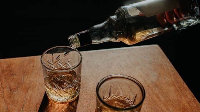 Whisky Pour from a bottle into a cut glass tumbler - stock photo